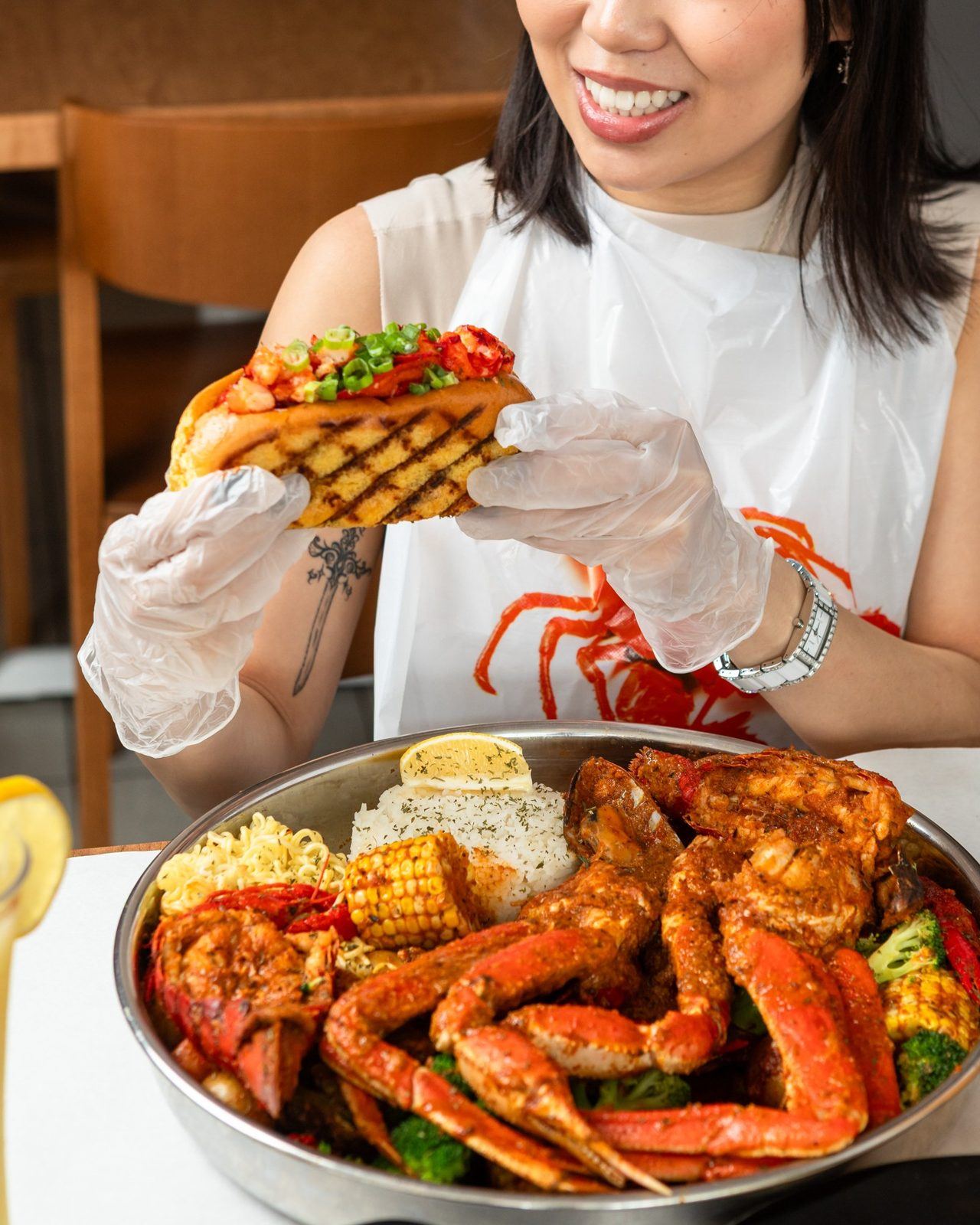 Guest with lobster roll over crab boil tray