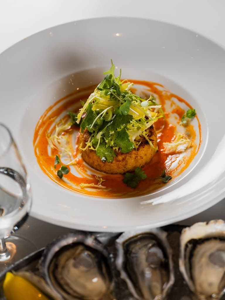 A herb-topped cake in orange sauce, oysters at the edge