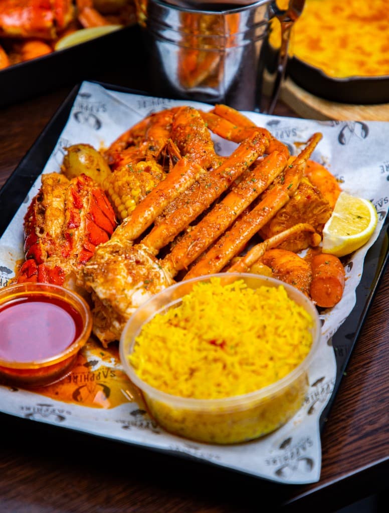 Snow crab, lobster, prawns, corn, potato, and yellow rice on Sapphire paper